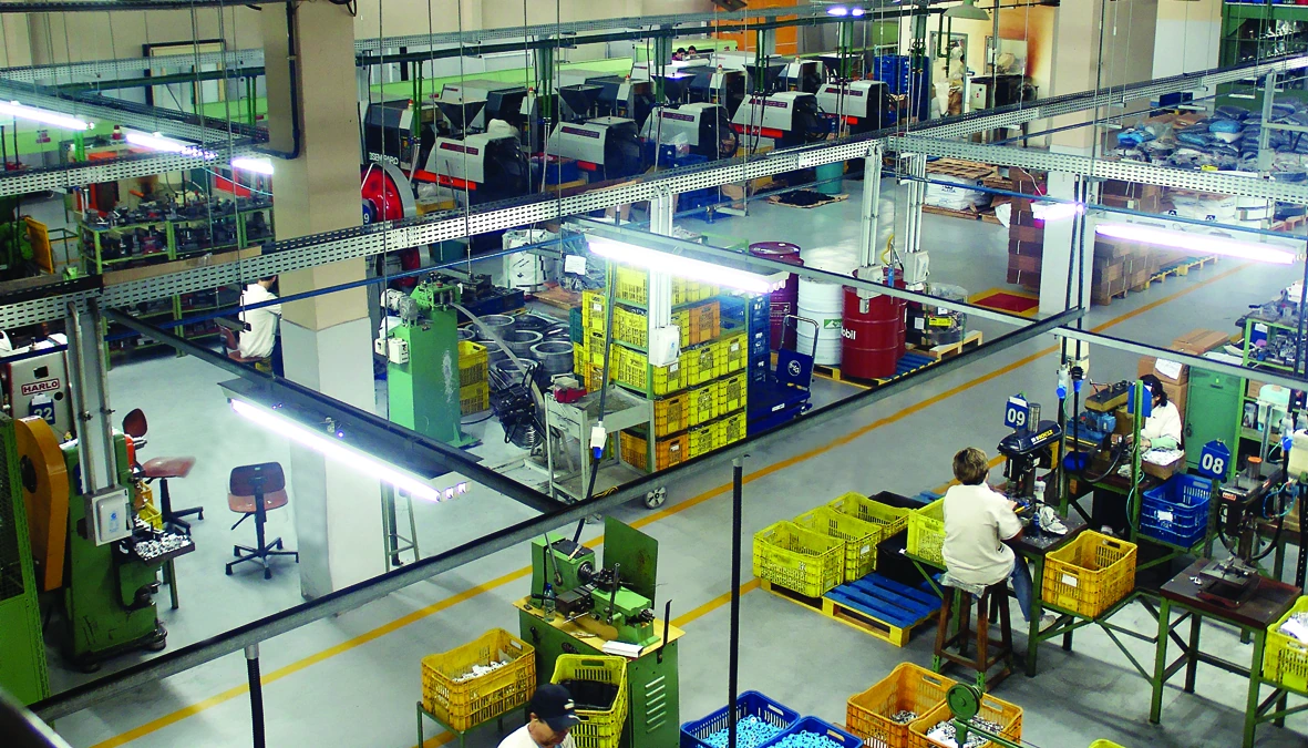 Área de produção FISE com máquinas, componentes organizados e pessoas trabalhando.