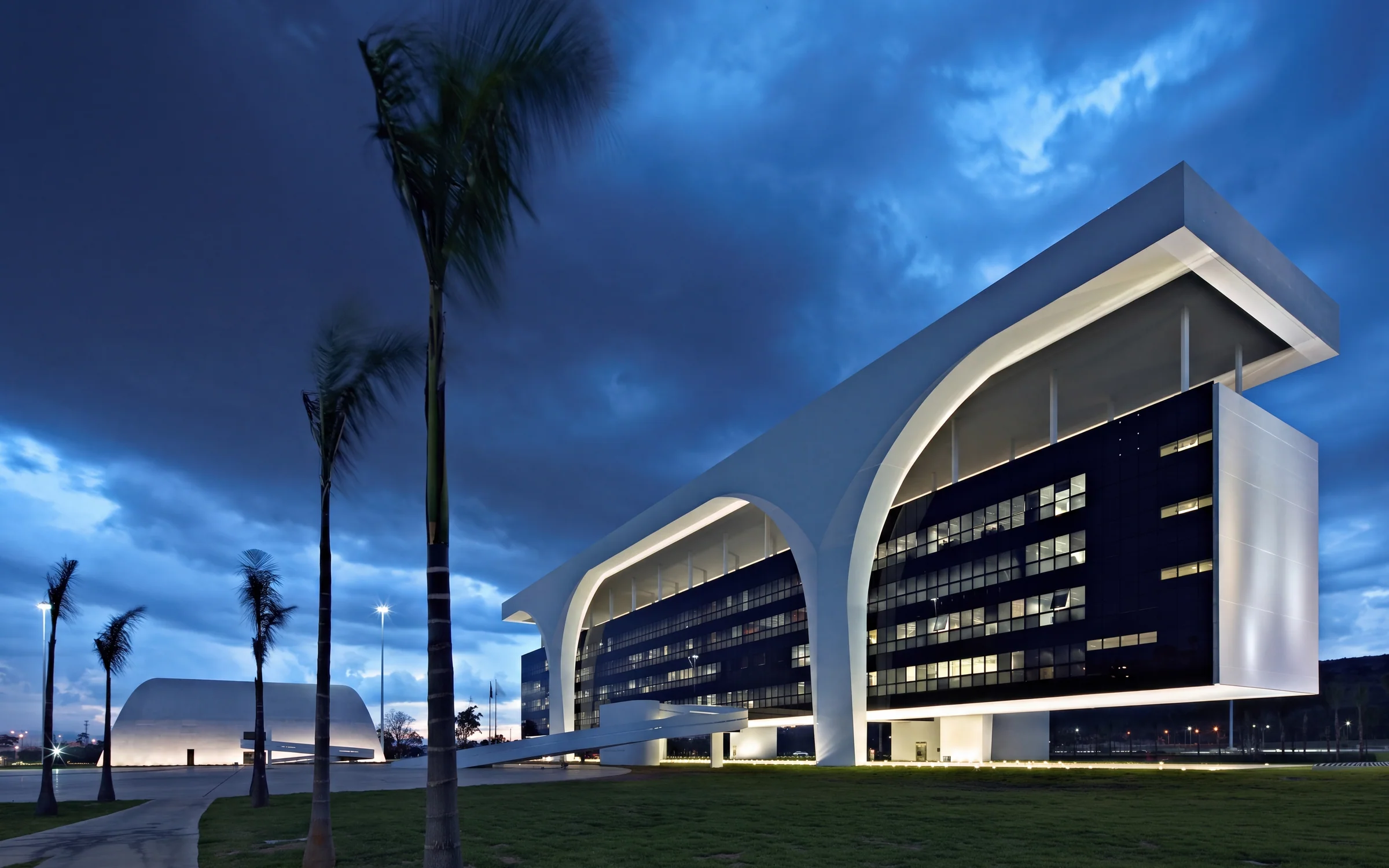 Edifícios curvos da Cidade Administrativa de Minas Gerais sob o céu do entardecer.