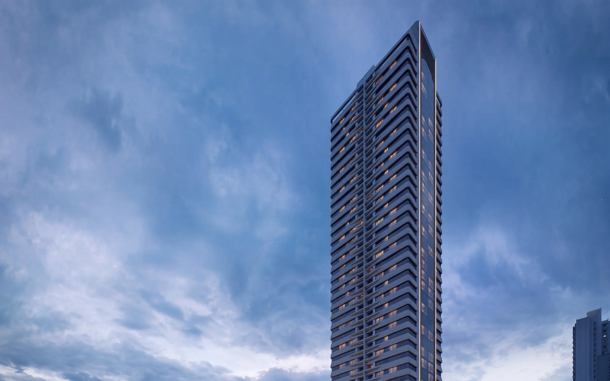 Ápice e fachada da torre La Città ao entardecer, com o entorno urbano visível na tomada vertical.