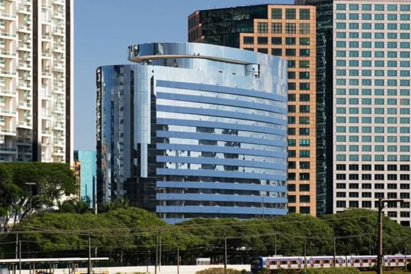 Edifício Landmark Nações Unidas visto da rua, com fachada azul envidraçada e contorno curvo.